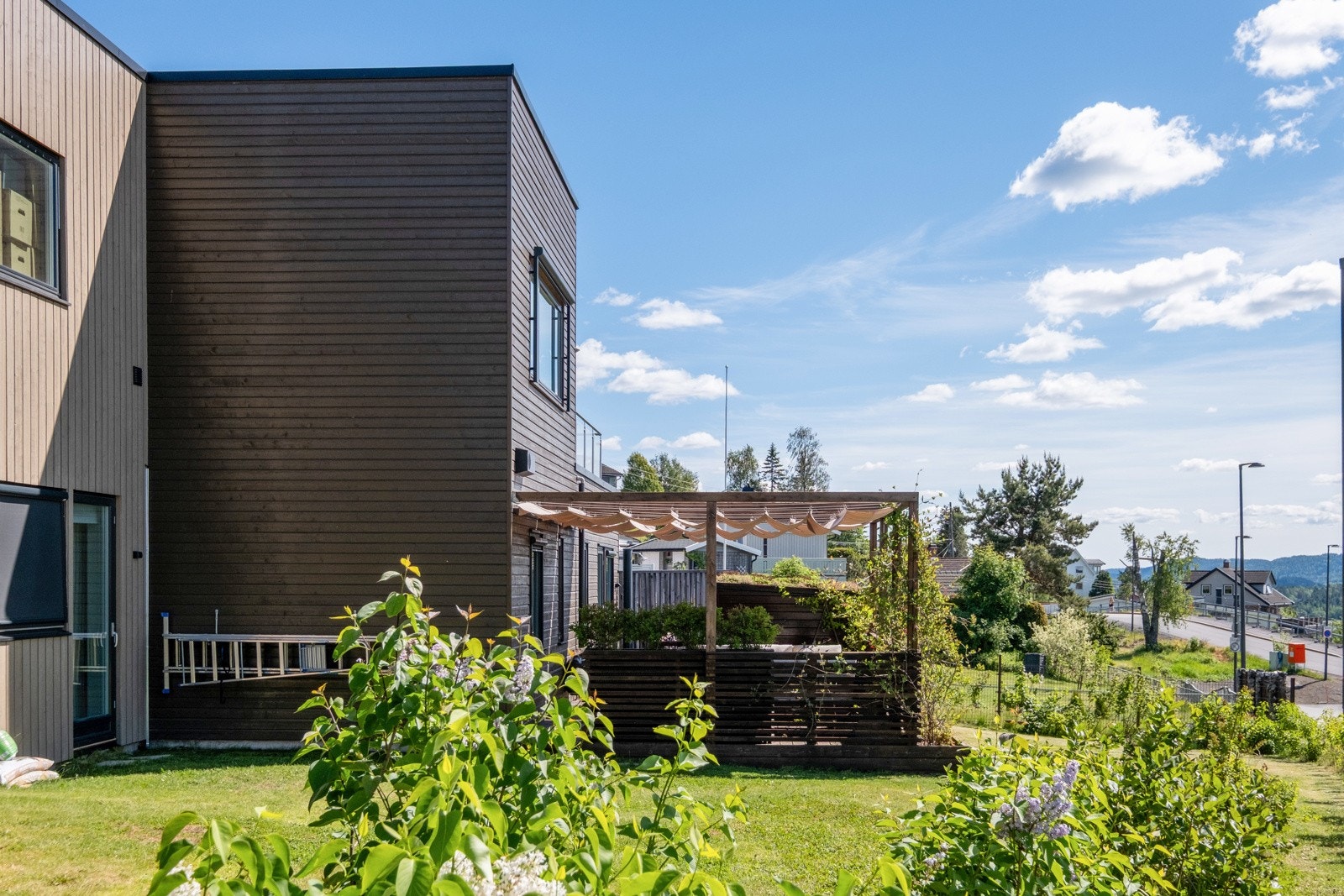 Hagen er pent opparbeidet med blomsterkasser, platting, badstue og plen. Galleribilde