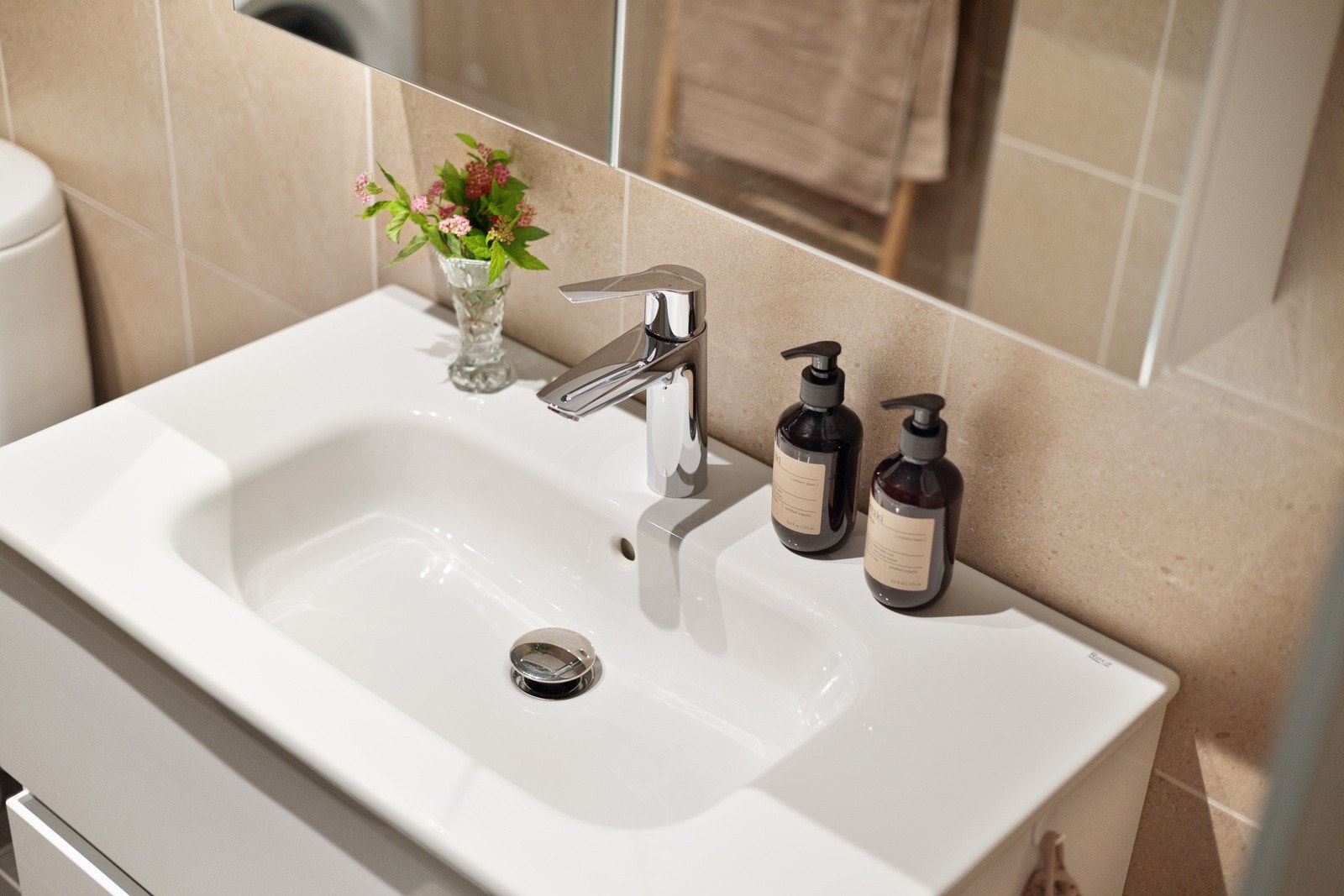 Moderne baderomsinnredning med skuffer og heldekkende servant, speilskap med belysning over. Galleribilde