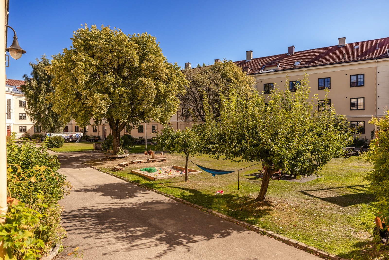Flott, felles bakgård som er meget pent opparbeidet med asfalterte gangveier, grønne plener, trær, og annen fin beplanting. Galleribilde