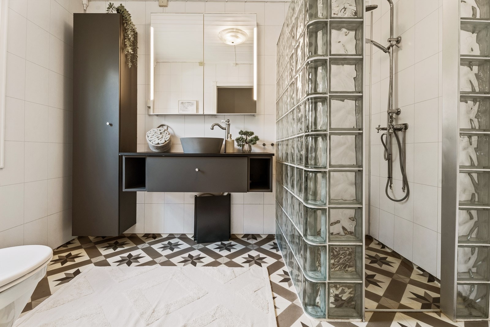 Rommet er innredet med dusjnisje med glassbyggerstein og regnfallsdusj, toalett, innredning med frittstående servant, speilskap og opplegg for vaskemaskin. Galleribilde