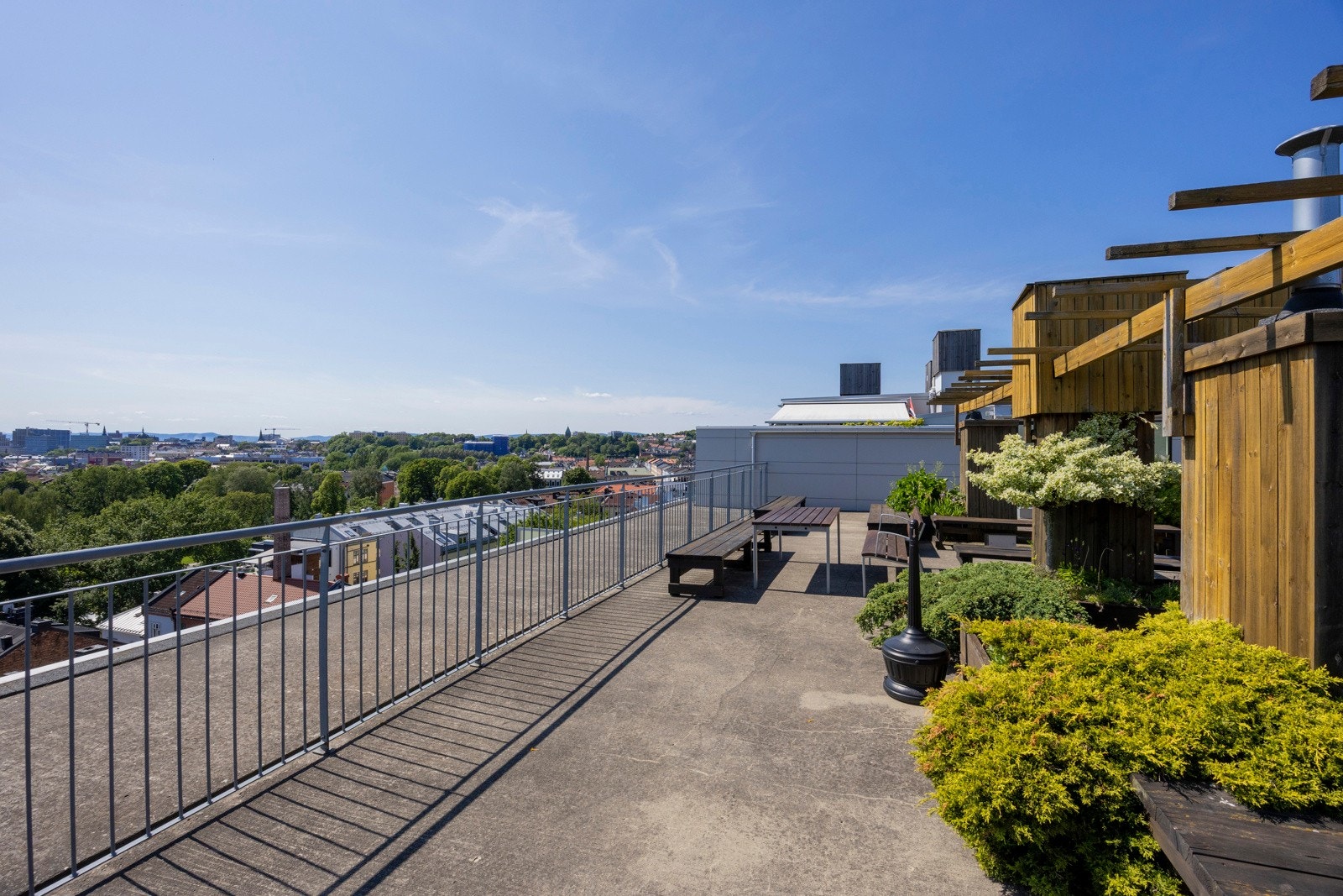 Takterrassen er pent beplantet med busker og flere sosiale soner. Galleribilde