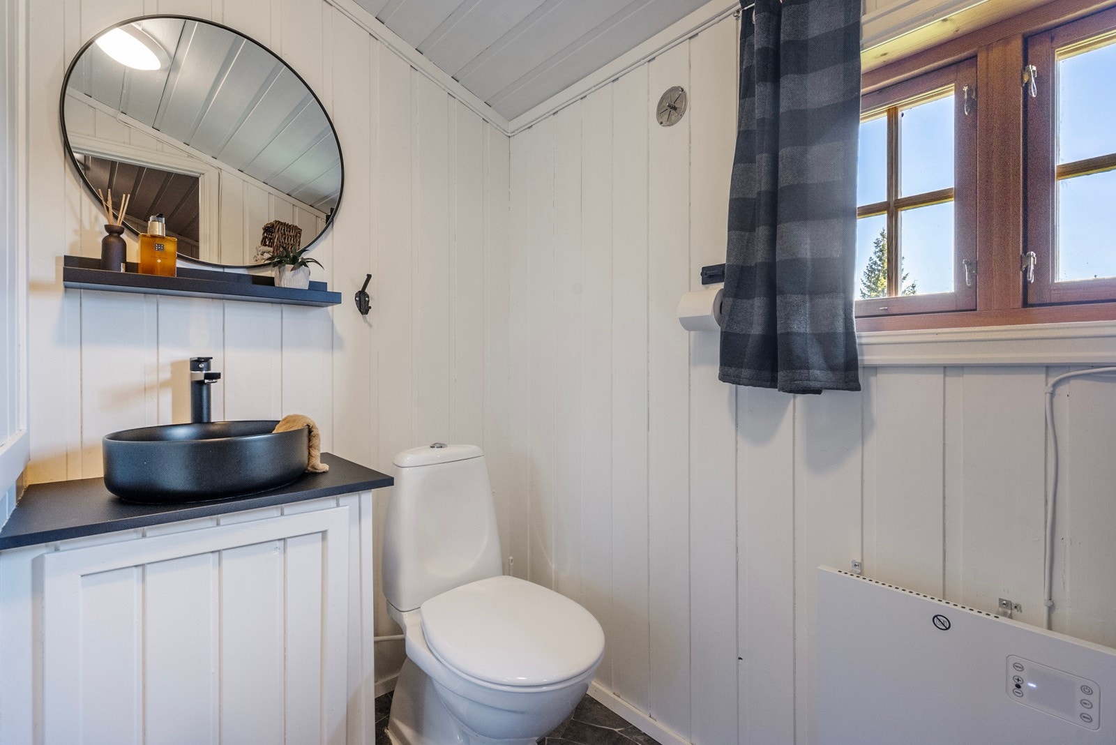 Badet er fra tilbyggingsår og har overflater av belegg på gulv og trepanel på vegger Galleribilde