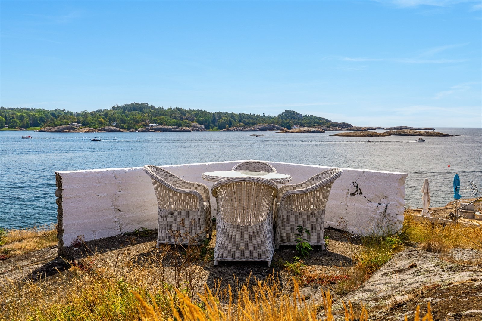 En naturterrasse på svaberget som går helt i ett med omgivelsene fra sjøsiden. Galleribilde