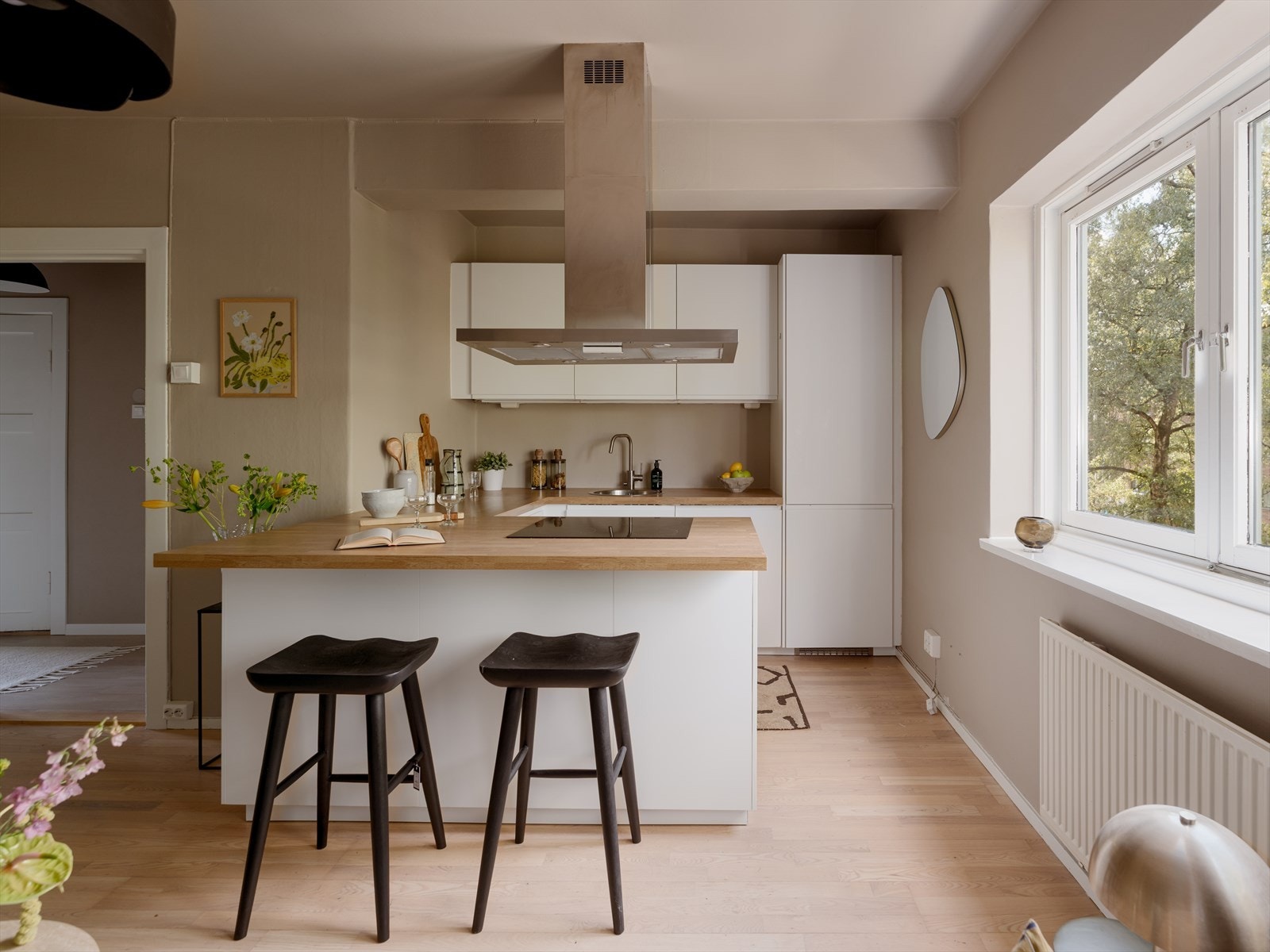 I hjørne av rommet er den stilrene kjøkkeninnredningen plassert. Innredningen er fra 2017 med hvite, matte fronter og laminat benkeplate. Galleribilde