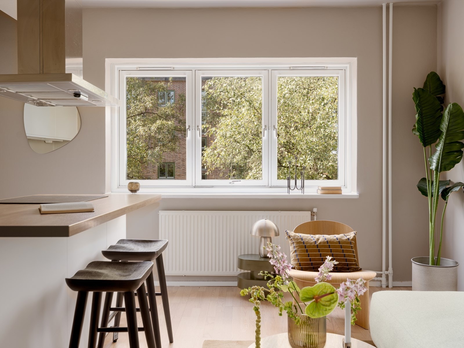 Store vinduer med dype karmer og grønt utsyn bidrar til en lys og behaglig atmosfære i rommet. Galleribilde