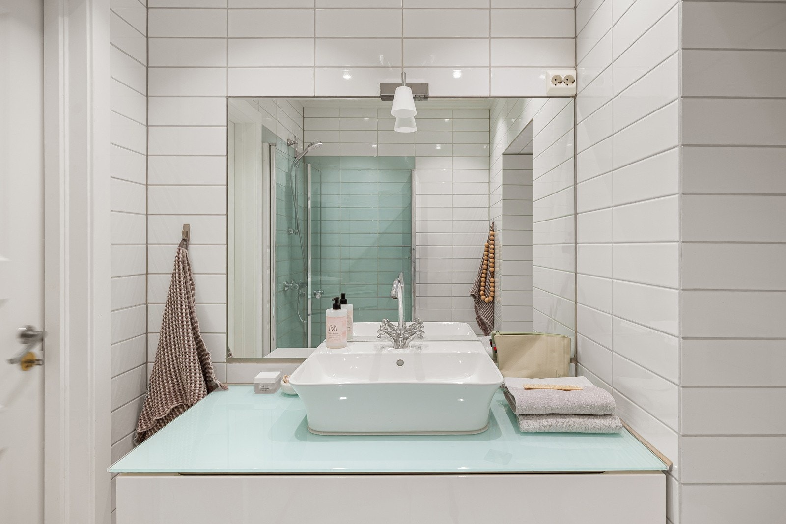 Moderne baderomsinnredning med skuffer og benkeplate med ovenpåliggende servant, innfelt speil med overlys. Galleribilde