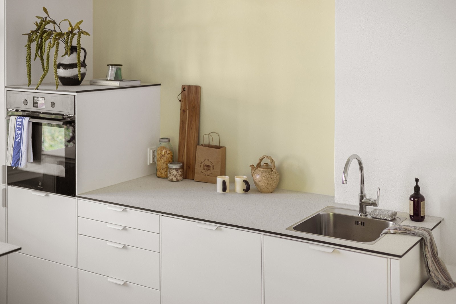 Stilren og moderne kjøkkeninnredning fra 2025 med hvite glatte fronter og laminert benkeplate med nedfelt oppvaskkum. Galleribilde