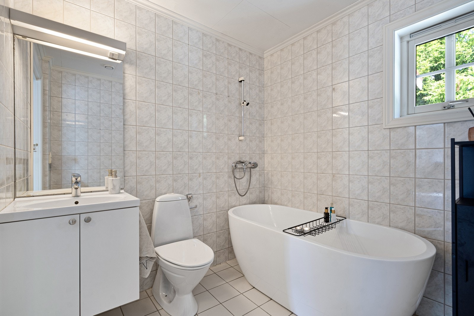 Badet er innredet med badekar, servant m/ skap og speil samt toalett Galleribilde