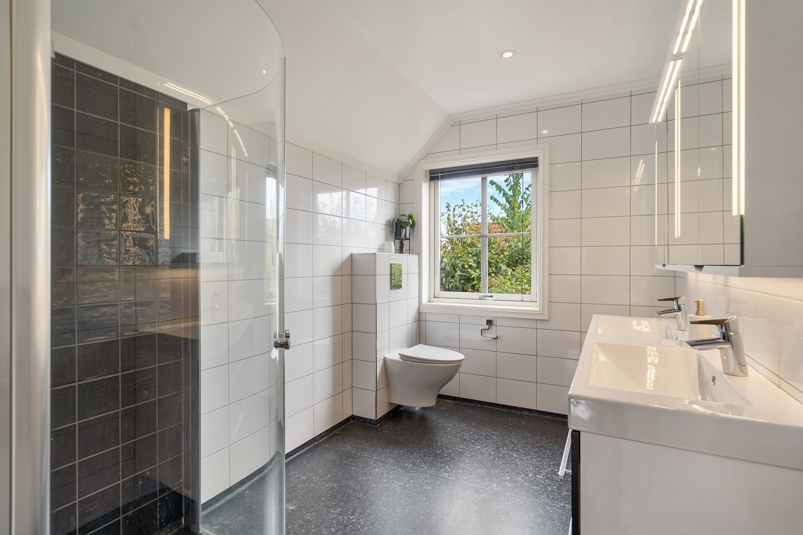 Badet er pusset opp i moderne farger og speilskap og vegghengt toalett Galleribilde