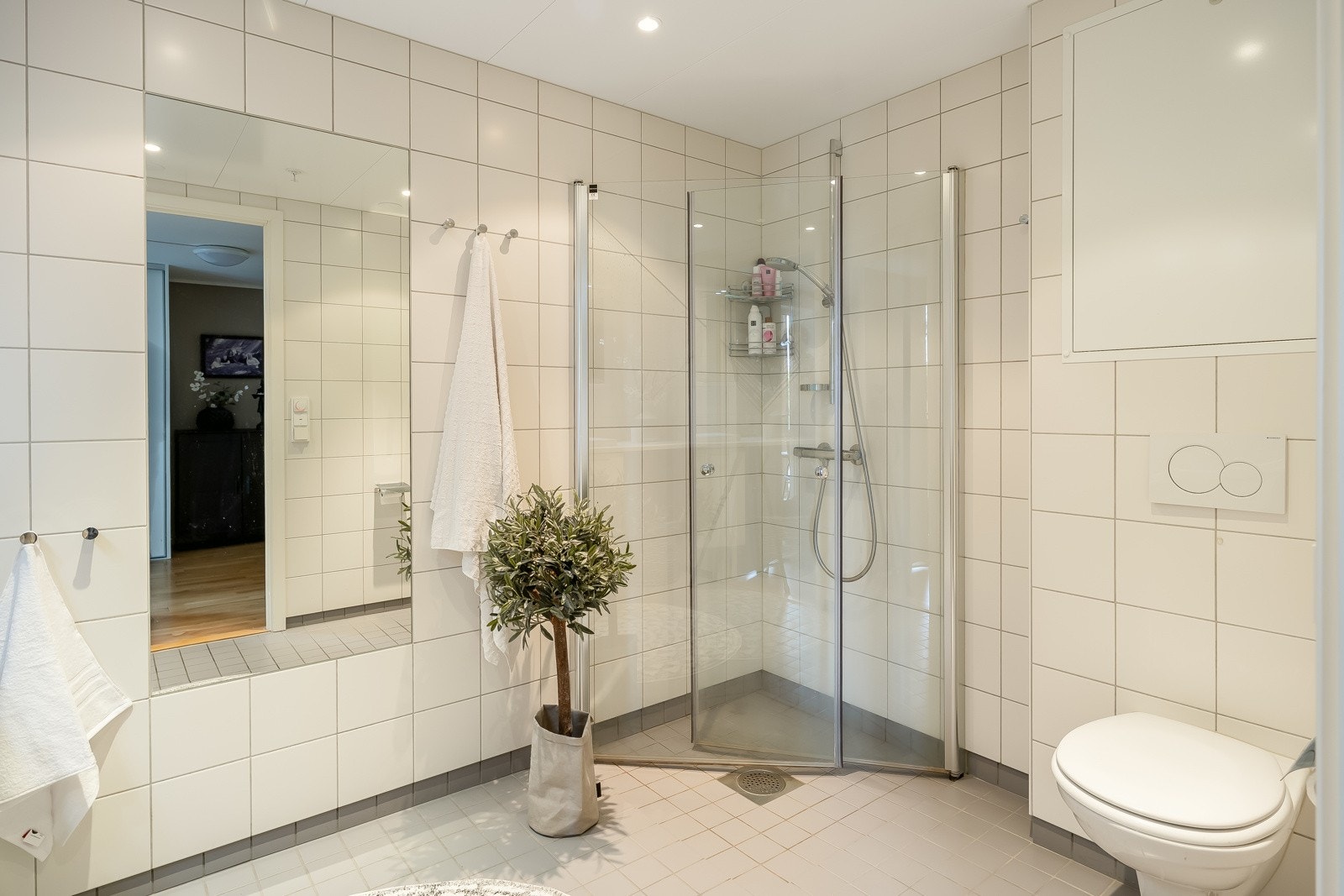 Badet måles til 6 kvm, og er innredet med innfellbare dusjvegger av glass, vegghengt toalett og servant med underskap. Galleribilde