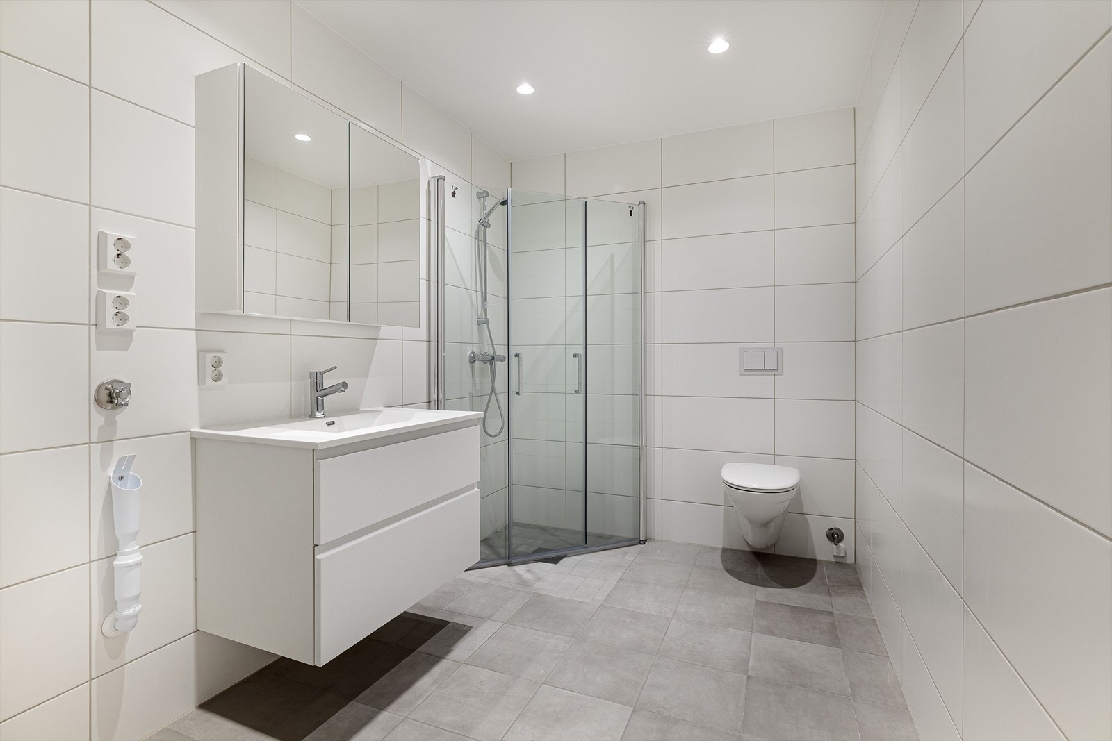 Leiligheten har et helt nytt og moderne bad/vaskerom. Baderommet har grå fliser på gulv med gulvvarme, hvite fliser på veggene, downlights i himlingen og balansert ventilasjon. Galleribilde