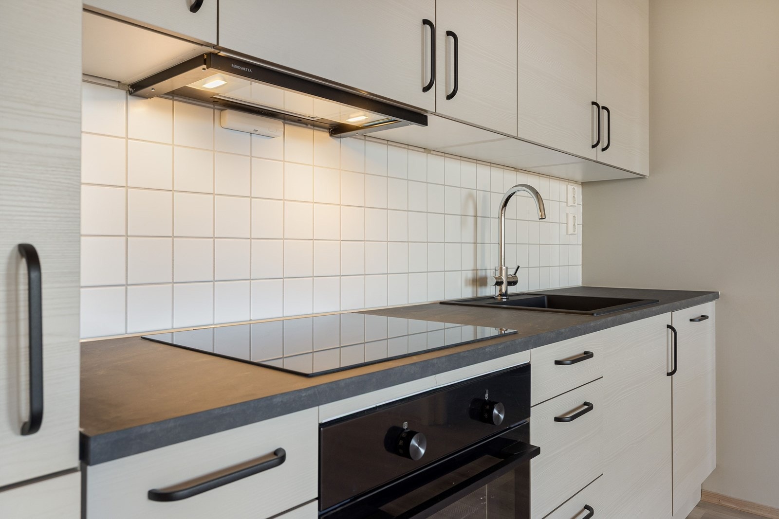 Innredningen har glatte fronter, laminert benkeplate med nedfelt oppvaskkum og lyse fliser i benkeryggen. Galleribilde