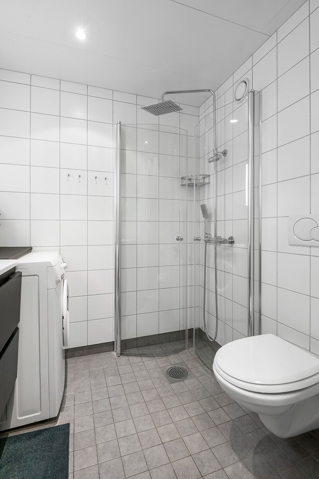 Badet er innredet med nedfelt servant, veggmontert toalett, dusjvegger/hjørne og opplegg for vaskemaskin. Galleribilde