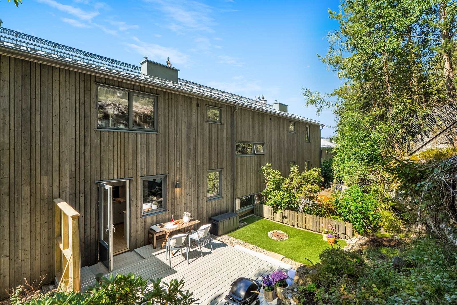 Moderne trehus med stor terrasse og hage. Boligen har flere vinduer som gir mye naturlig lys. Galleribilde
