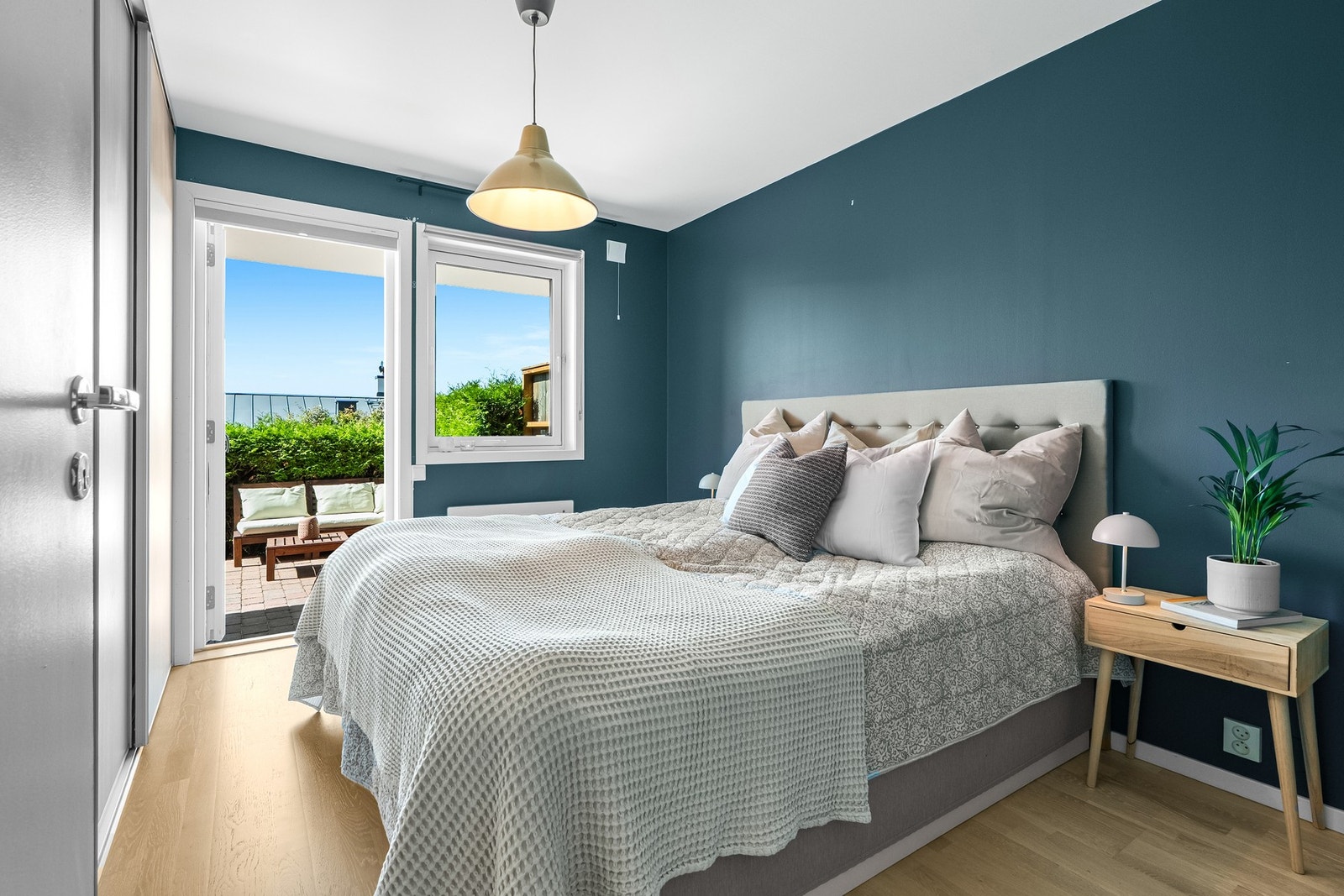 Lyst soverom med direkte utgang til uteplass. Vegger i mørk blå farge og store vinduer som gir mye lys. Galleribilde