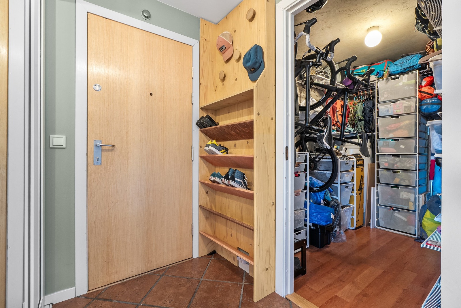 Entré med skohyller og tilknyttet bod med organisert lagringsplass og oppheng for sykler. Galleribilde