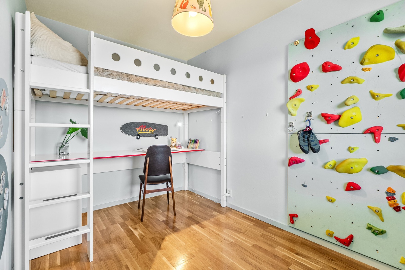Loftseng med skrivebord under og klatrevegg på høyre side. Veggene er lysegrå og gulvet er parkett. Galleribilde