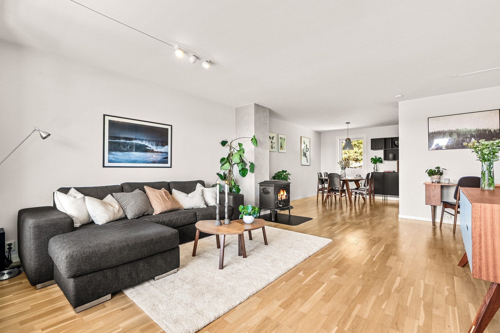 Lys og romslig stue med peis, åpen løsning til spiseområde og kjøkken. Galleribilde