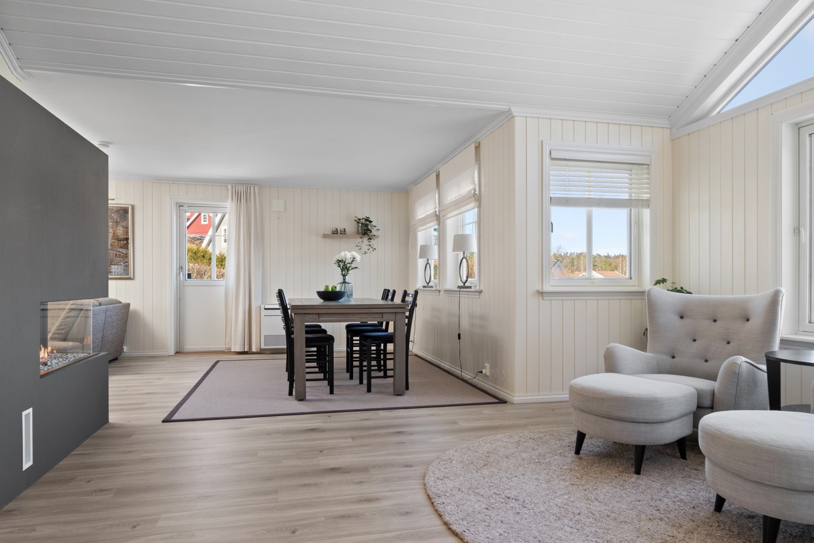 Dagslyset som strømmer inn via sprossevinduer i fire himmelretninger gjenspeiles fint i de lysmalte overflatene, og stuen har tidsmessig, enstavs laminat på gulvet. Galleribilde