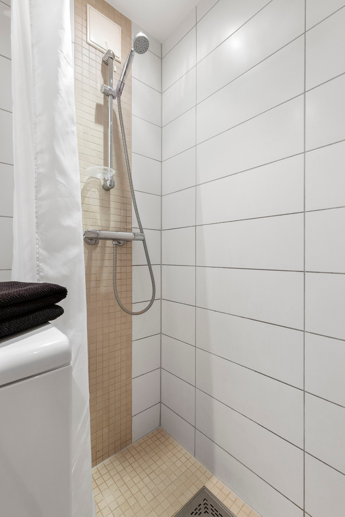 Rommet er innredet med nedfelt servant i underskap, speil med belysning, veggmontert toalett og opplegg for vaskemaskin. Galleribilde