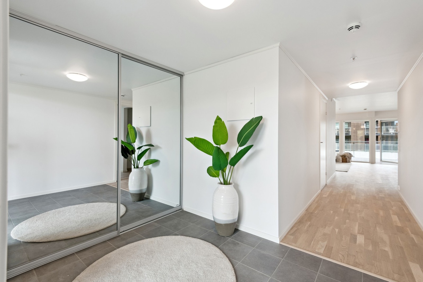 Romslig gang med skyvedørsgarderobe og flislagt gulv. Galleribilde