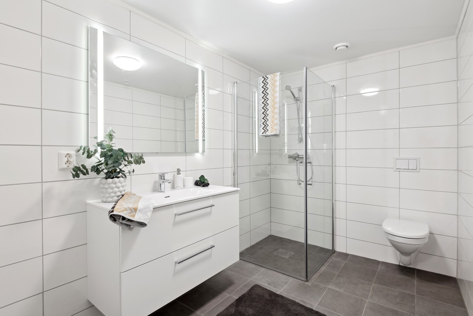 Romslig bad med dusjhjørne og veggfestet toalett. Galleribilde