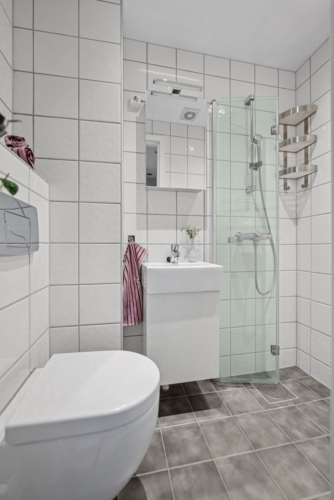 Praktisk baderom i tidløs stil med flislagte gulv og vegger i lyse farger. Galleribilde