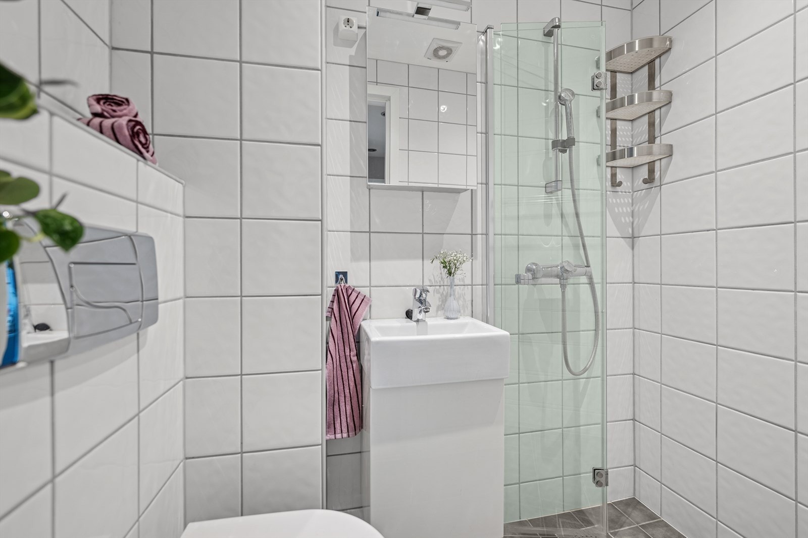 Badet byr på smarte løsninger med sammenleggbare dusjdører, samt vaskeservant med underskap og overskap med speilfronter. Galleribilde