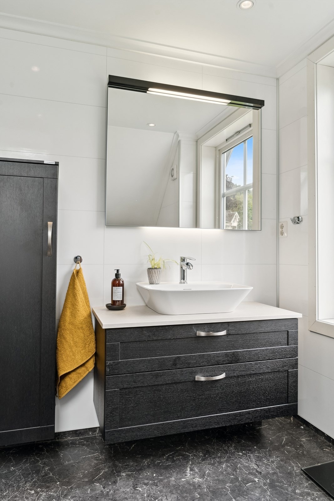 Mørk innreiing med stilfull bolleservant, god lagringsplass og speil med integrert belysning. Galleribilde