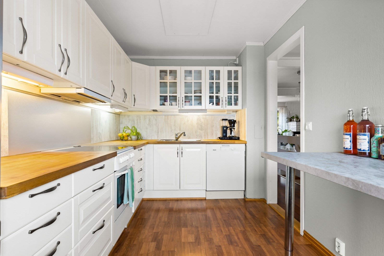 Tidløst kjøkken som ble overflatemalt i 2022. Benkeplater ble pusset ned og lakket samt ny kjøkkenkran i 2025. Galleribilde