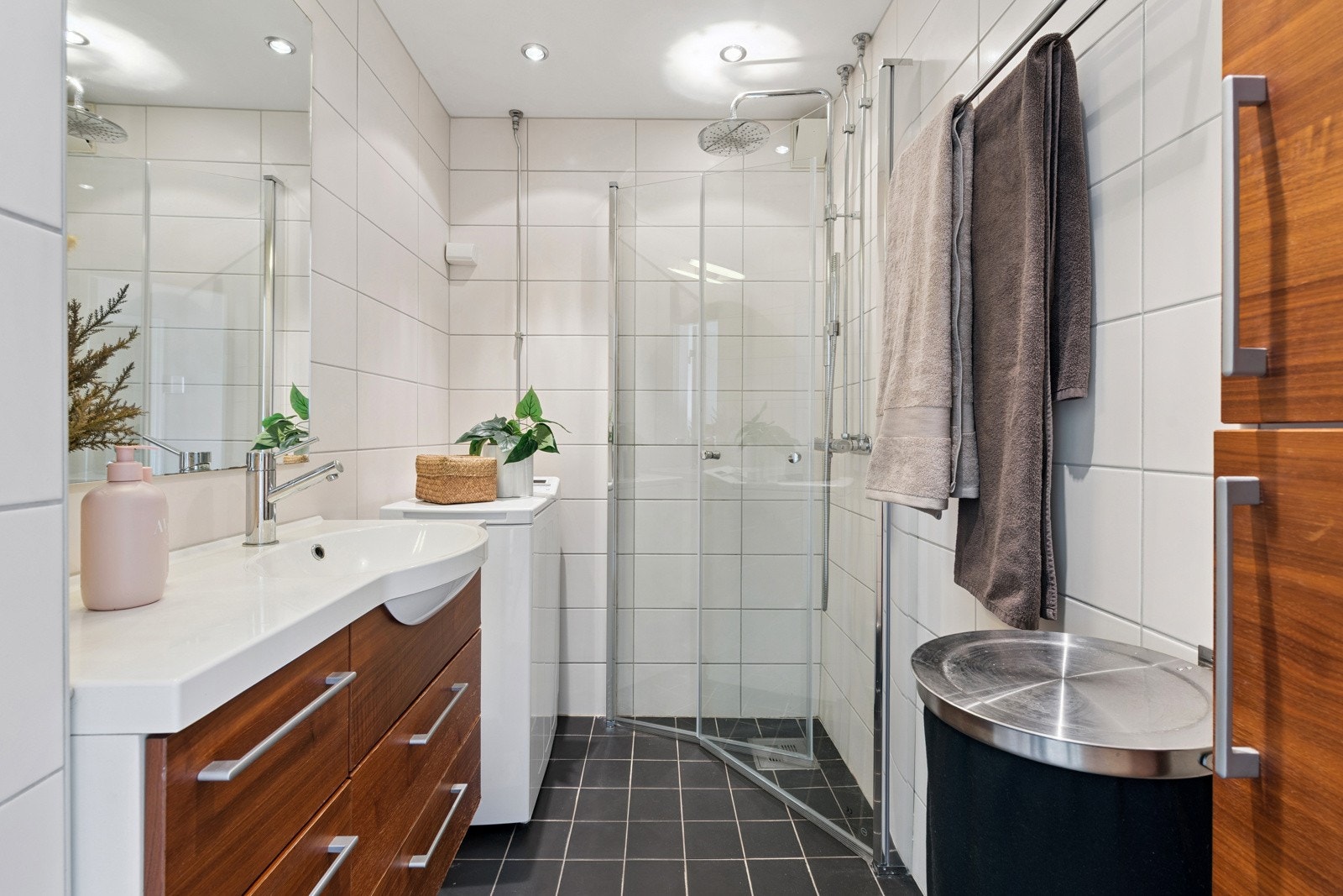 Badet er utstyrt med dusj med nye inn- utadslående dusjvegger (fra 2025), servant med underskap, speil med overlys, samt veggskap. Galleribilde