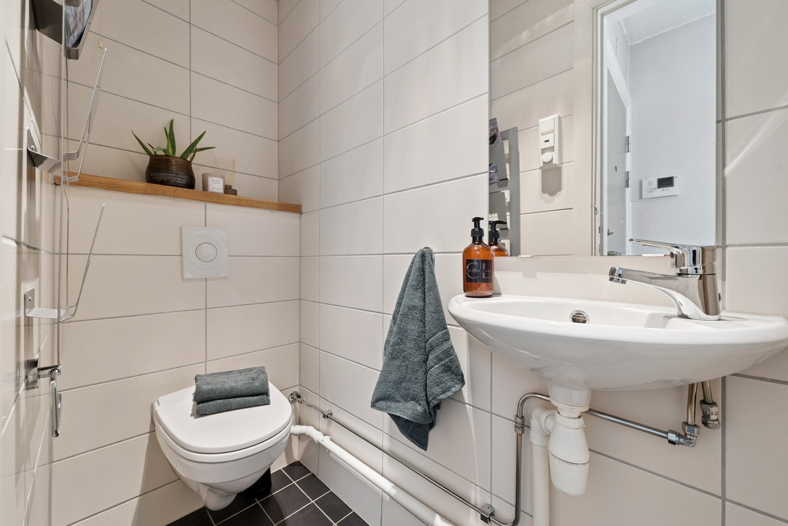 Separat flislagt toalettrom med varmekabler i gulv. Rommet er utstyrt med veggmontert klosett og servant med speil over. Galleribilde