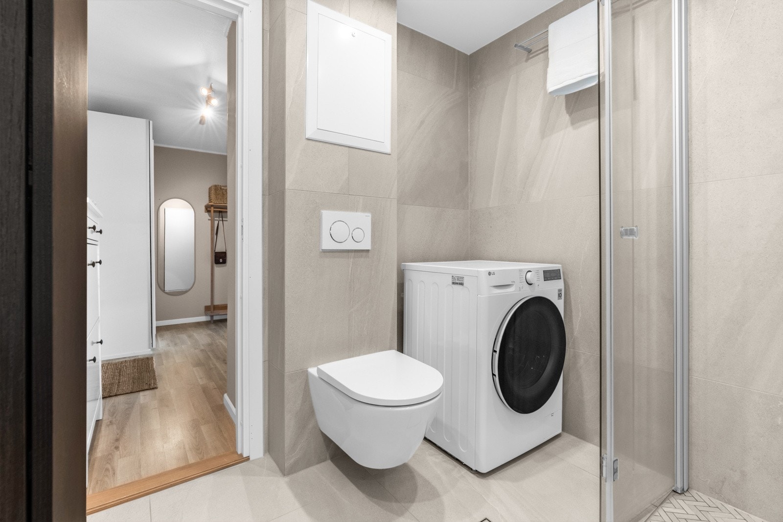 Det er videre håndklehenger på vegg, vegghengt skap, dusjhjørne med hånddusj og regndusj, vegghengt toalett og opplegg for vaskemaskin. Galleribilde