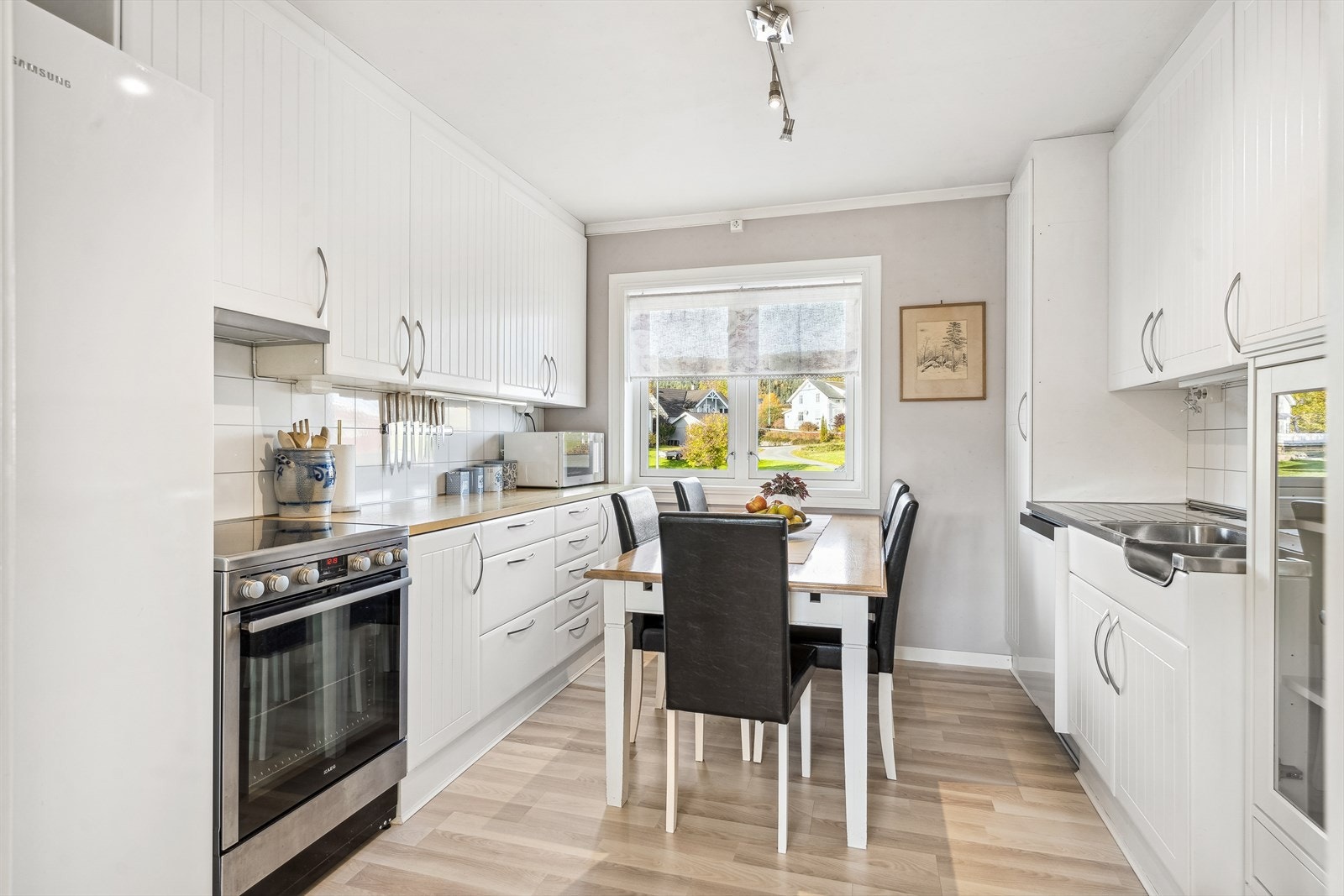 Stilrent kjøkkenet som er innredet takhøy på 2 vegger og har eldre Norema skapstammer med nyere kjøkkenfronter - lyse med riller. Galleribilde