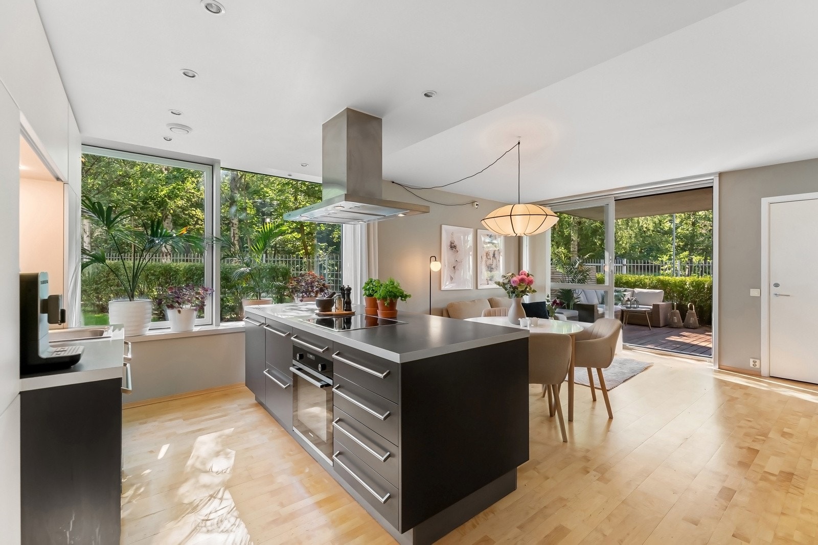 Stor og luftig stue og kjøkken i særs velfungerende, åpen løsning - Store vindusflater i to himmelretninger rammer inn det frodige utsynet. Galleribilde