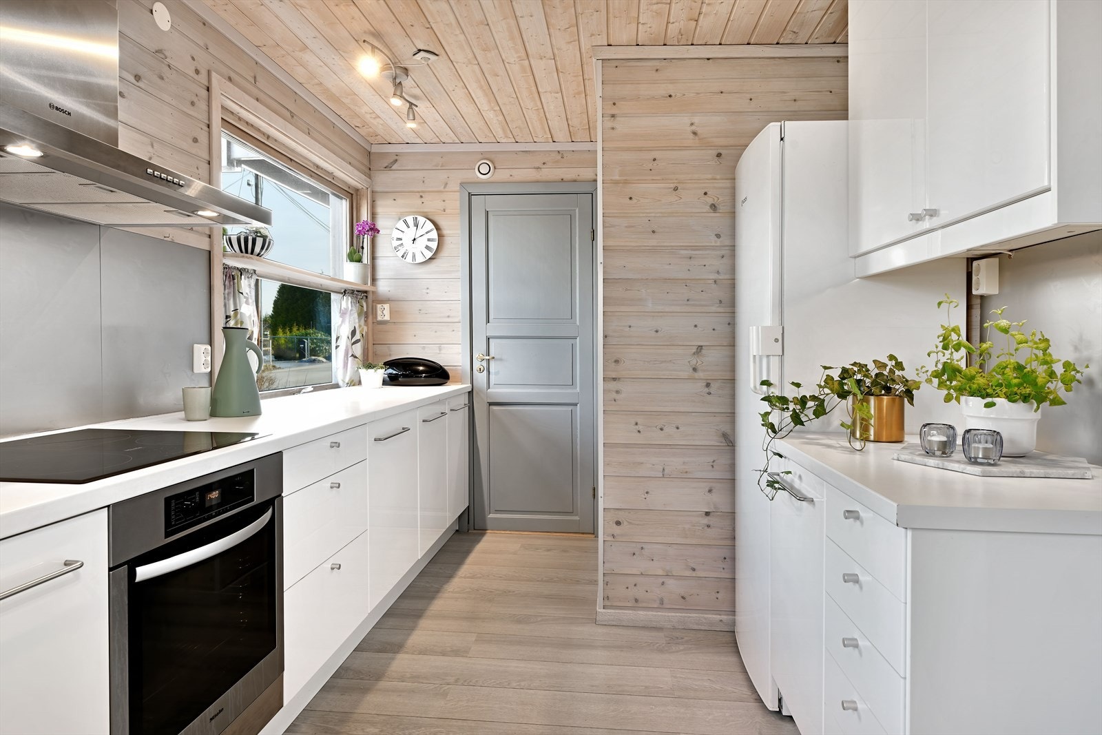 Flott høyglans kjøkkeninnredning med Miele komfyr med platetopp Galleribilde