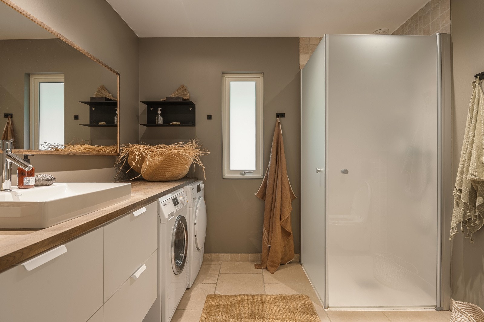 Lekkert baderom fra 2018 med vegghengt wc, servant med skuffer, dusjhjørne med innad slående dører og opplegg for vaskemaskin og tørketrommel. Galleribilde