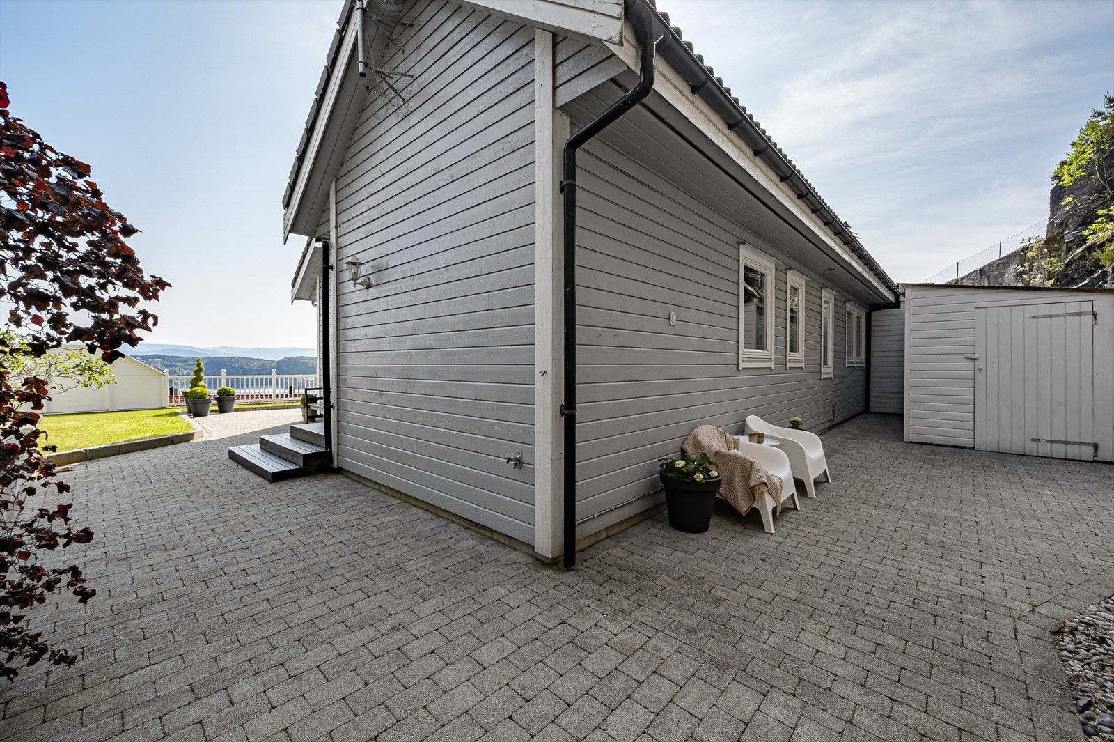 Skjermet del av eiendommen med belegningsstein, sittekrok og utebod. Galleribilde