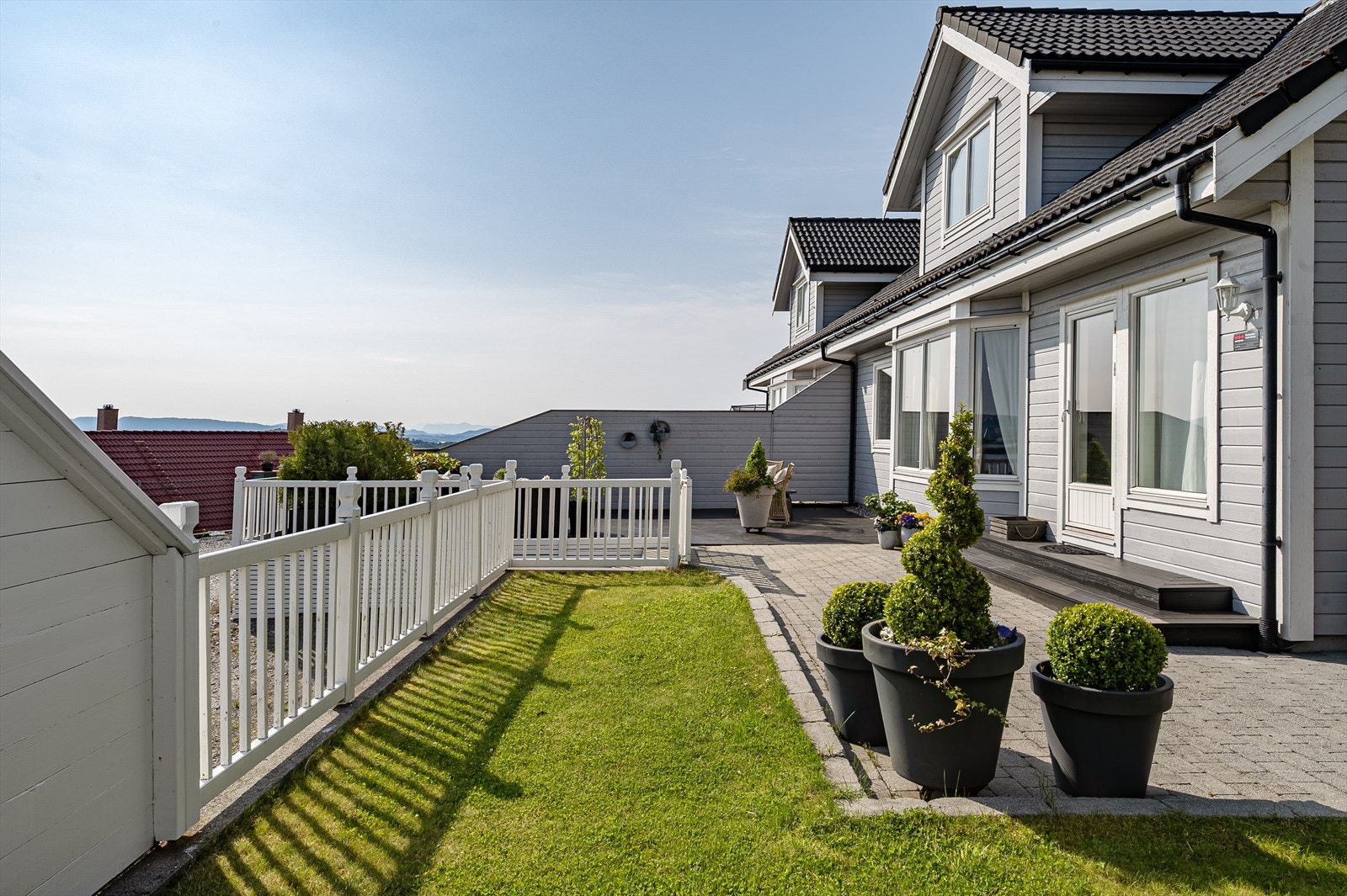 Pent opparbeidet uteområde med belegningsstein, plen og beplantning. Galleribilde