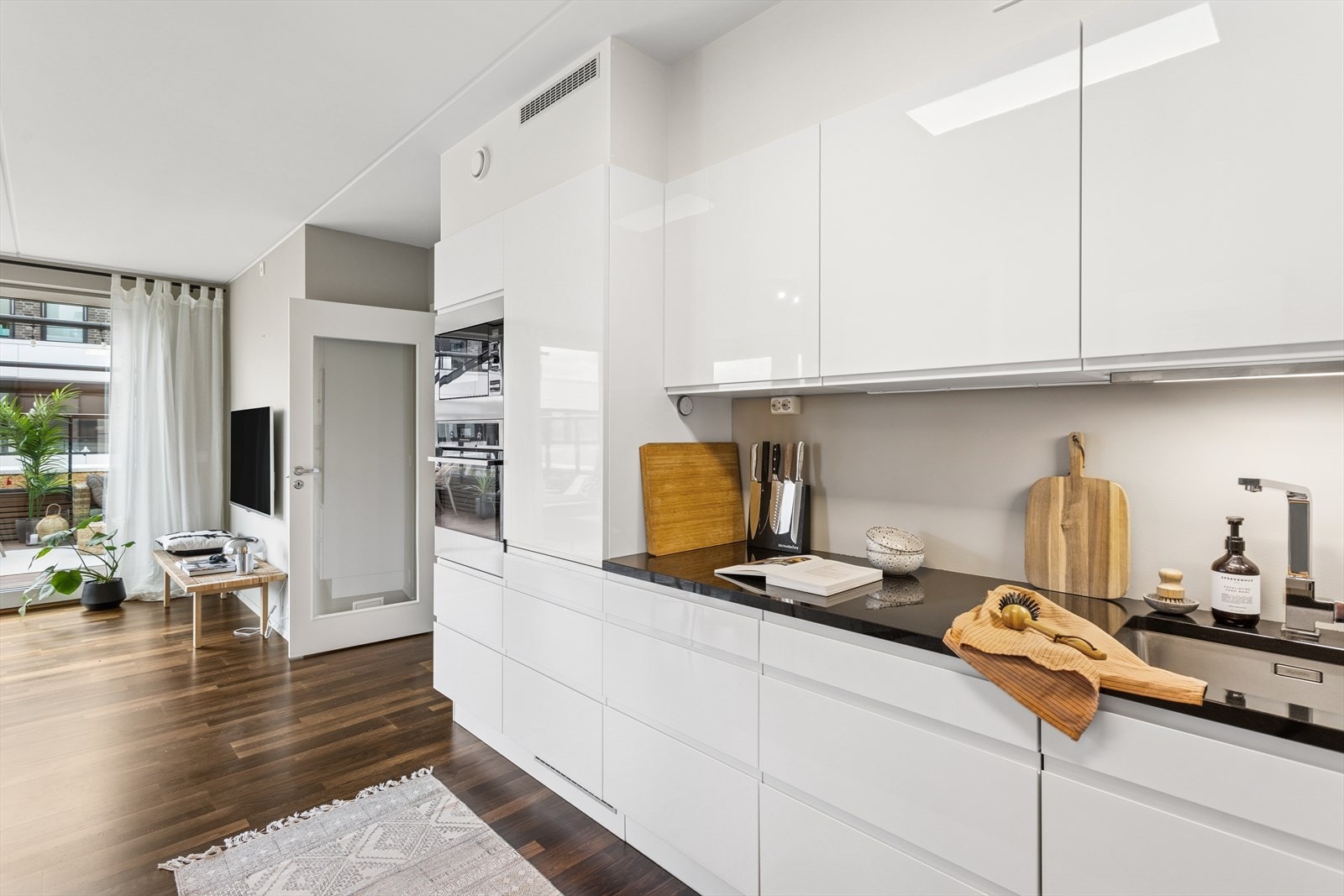 Stilrent og innholdsrikt kjøkken med glatter fronter, benkeplate av stein med underlimt vask. Galleribilde