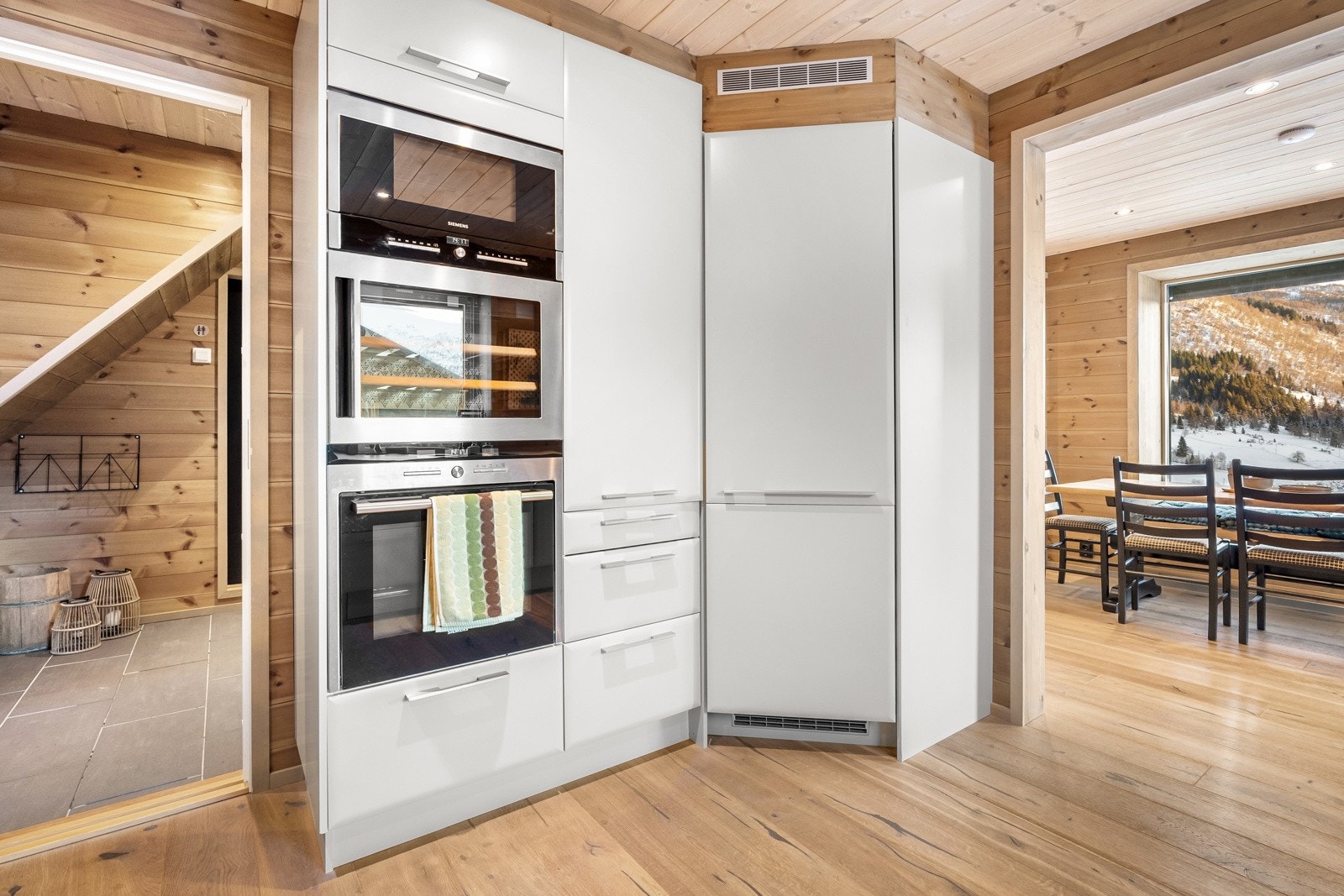 Integrerte hvitevarer fra Siemens med stor koketopp, steikeovn, oppvaskmaskin (Electrolux) og mikrobølgeovn og kjølehjørne. Galleribilde