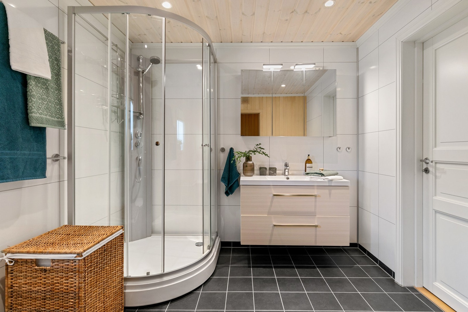 Rommet er flislagt og har gulvvarme, og er utstyrt med heldekkende servant med skuffer under, speilskap, dusjkabinett og gulvstående toalett. Galleribilde