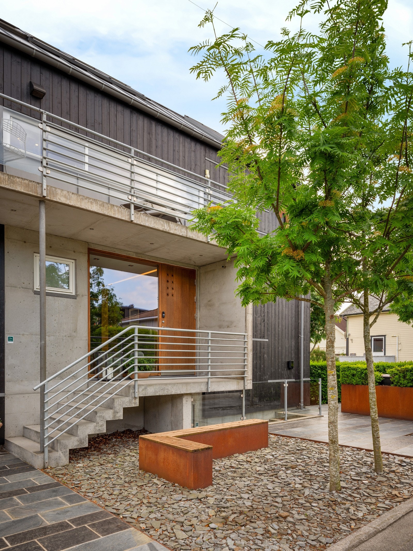 Flott opparbeidet uteområde med skiferfliser og corteenstål sittebenker og plantekasser Galleribilde