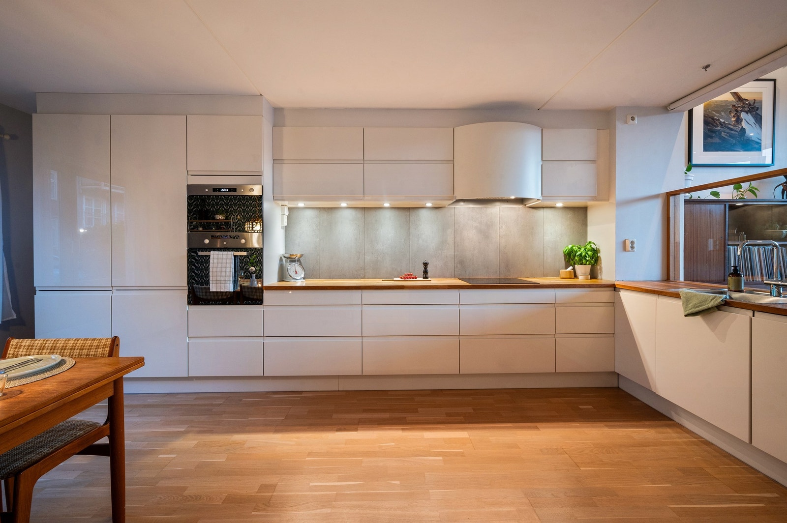 Innredningen er tidløs med hvite slette fronter, heltre benkeplate med nedfelt oppvaskkum. Hvitevarene består av integrert induksjonstopp, stekeovn, micro, oppvaskmaskin og kjøl/fryseskap. Galleribilde