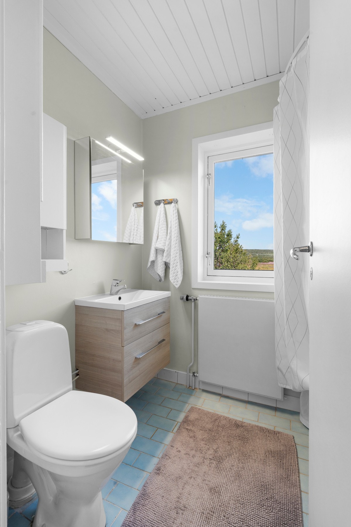 Badet har toalett, servant med belyst overspeil, badekar med dusjhode. Galleribilde