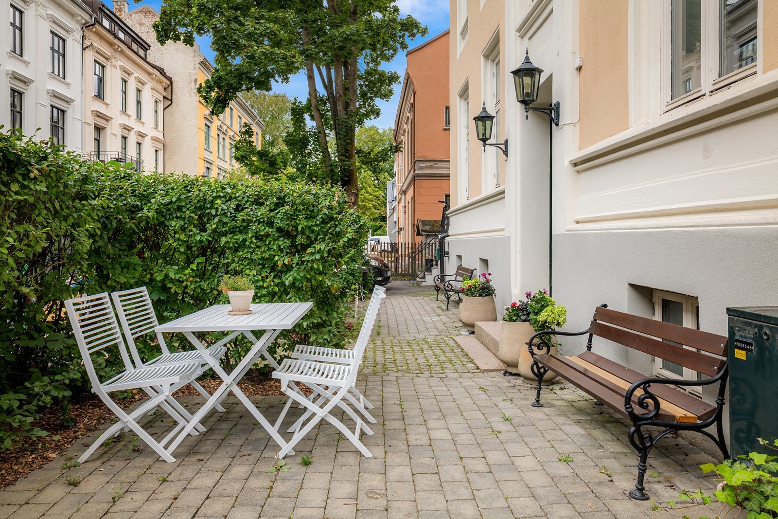 Brostensbelagt inngangsparti med skjermende hekk og sittegrupper Galleribilde