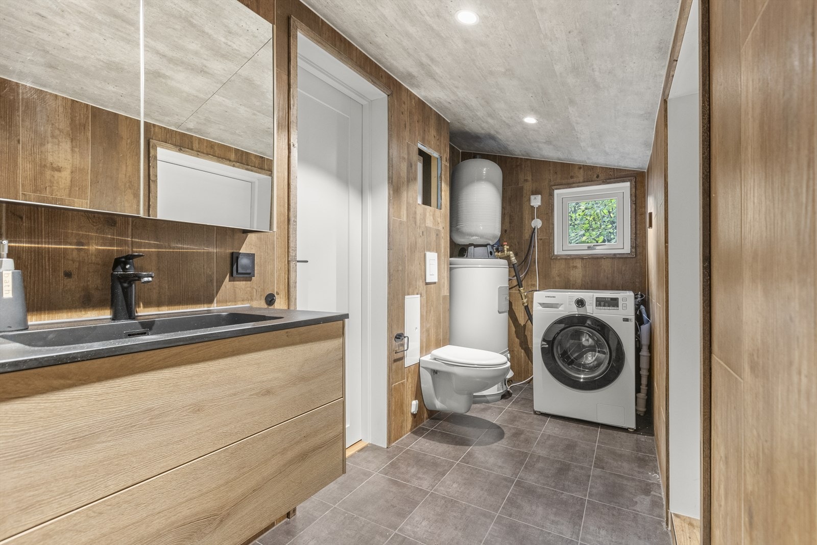 Innredet med vegghengt toalett og opplegg for vaskemaskin. Galleribilde