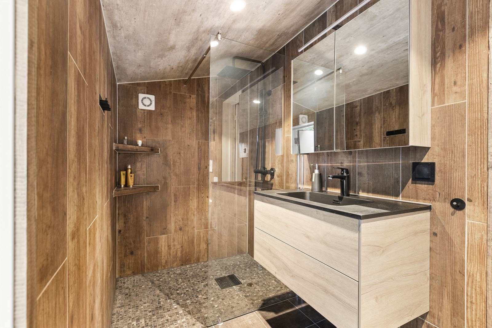 Videre er baderommet innredet med heldekkende servant med skuffeinnredning over speilskap over. Galleribilde