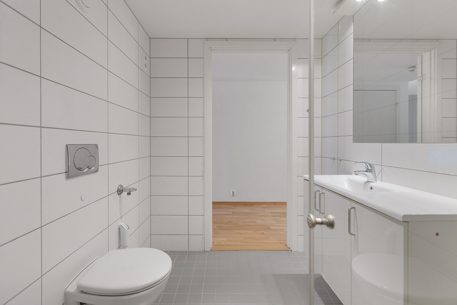 Tidsriktig inredning med veggmonterte dusjdører, servant med underskap, speil med lys, samt veggmontert WC. Her er det også opplegg for vaskemaskin. Galleribilde