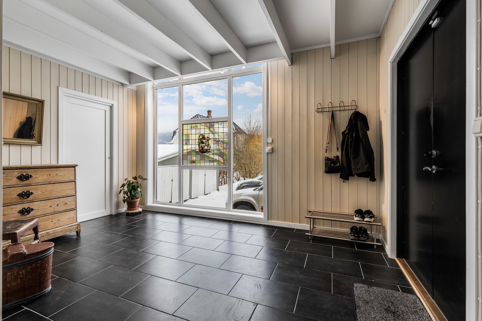 Lys og romslig entré med store vinduer, lyse vegger og mørke fliser på gulvet med varme. Galleribilde